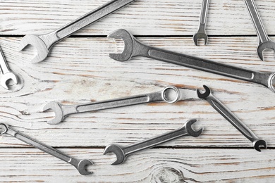 New wrenches on wooden background, top view. Plumber tools