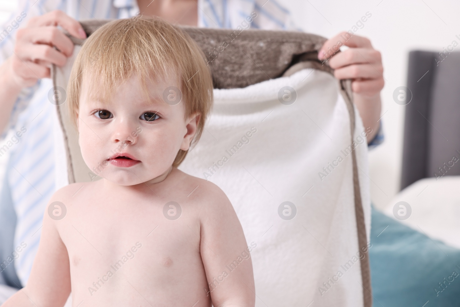 Photo of Mother wrapping her cute little baby with towel after bathing on bed