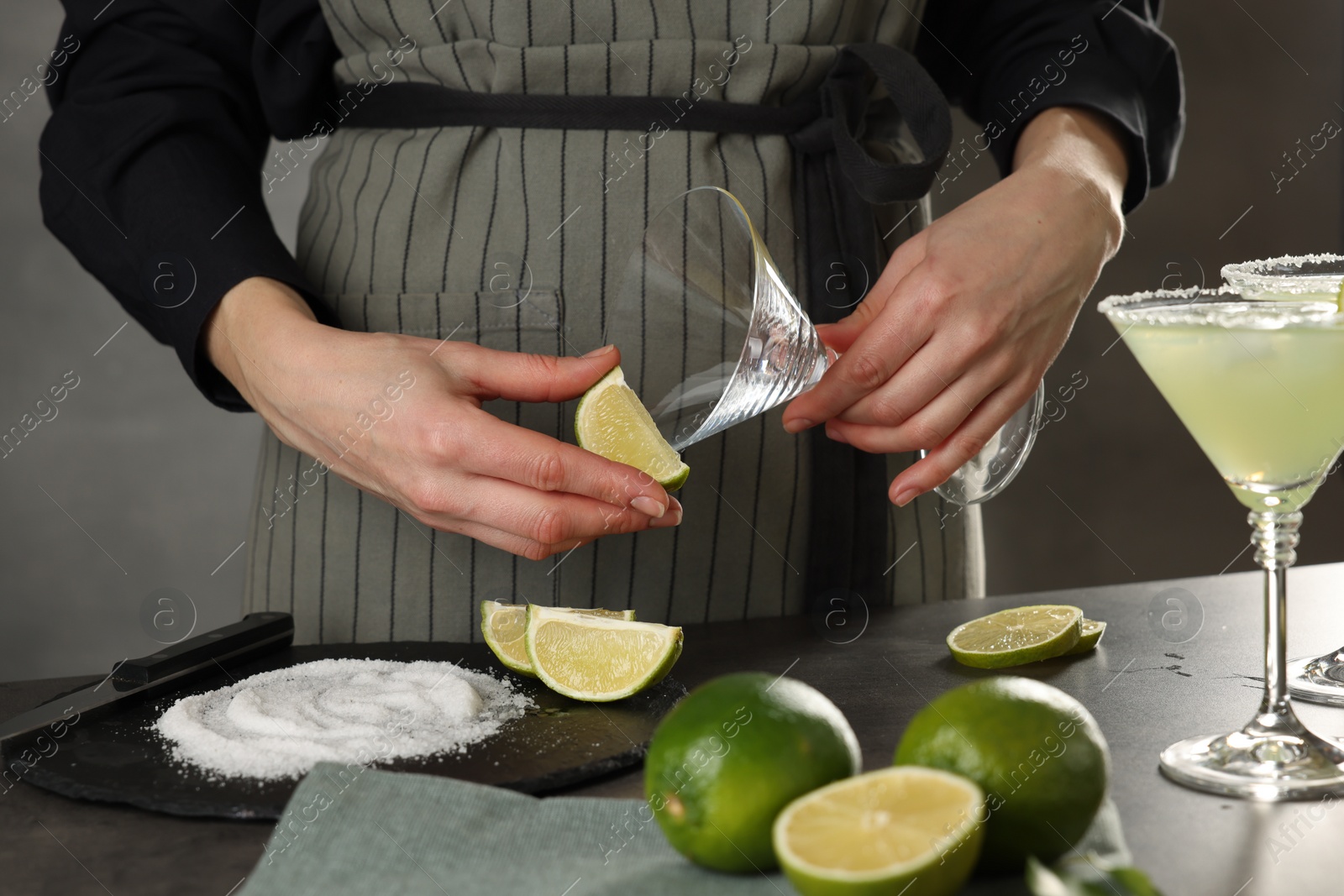 Photo of Woman making delicious Margarita cocktail at grey table, closeup