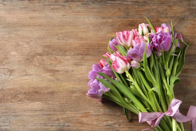 Photo of Beautiful bouquet of colorful tulip flowers on wooden table, top view. Space for text