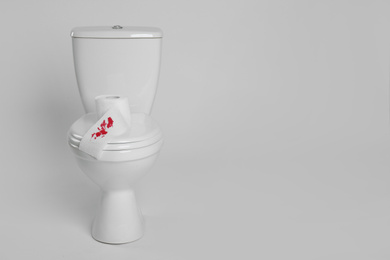 Photo of Paper with blood stain on toilet bowl against white background. Hemorrhoids concept