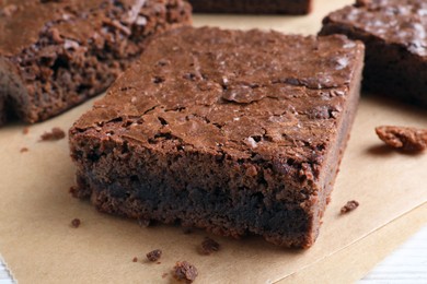 Photo of Delicious chocolate brownies on parchment paper, closeup
