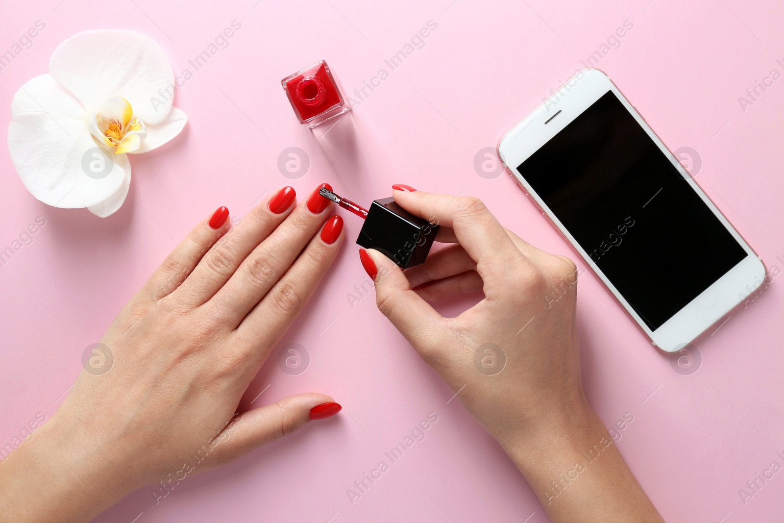 Photo of Woman applying bright nail polish on color background, top view