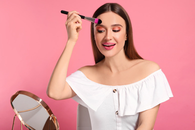 Beauty blogger doing makeup on pink background