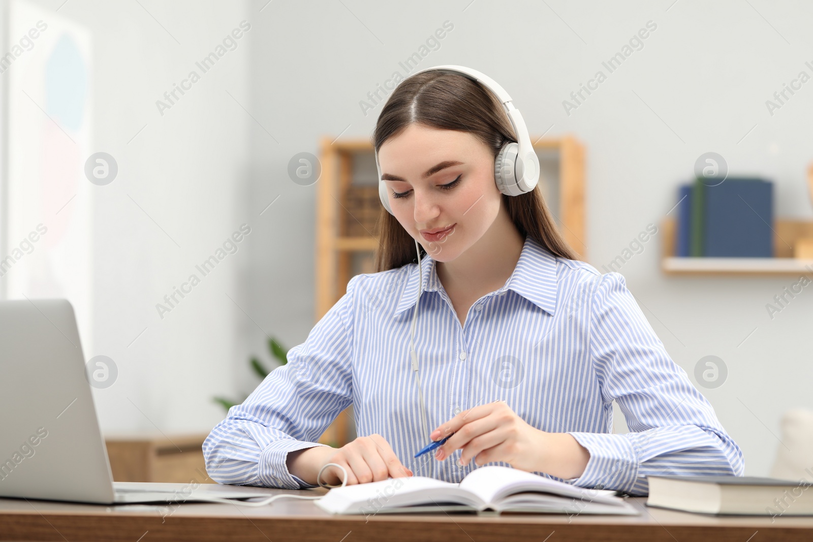 Photo of E-learning. woman taking notes during online lesson at table indoors