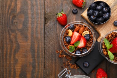 Photo of Tasty granola, berries and nuts on wooden table, flat lay. Space for text