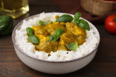 Delicious rice and chicken with curry sauce served on wooden table, closeup