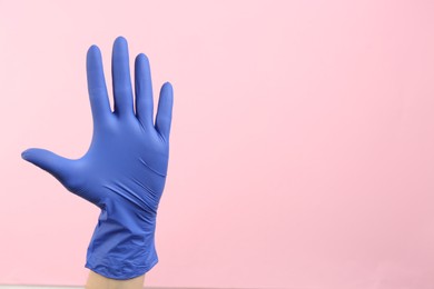 Photo of Person in medical gloves on pink background, closeup of hand. Space for text