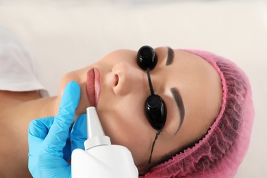 Photo of Woman undergoing laser tattoo removal procedure in salon, closeup