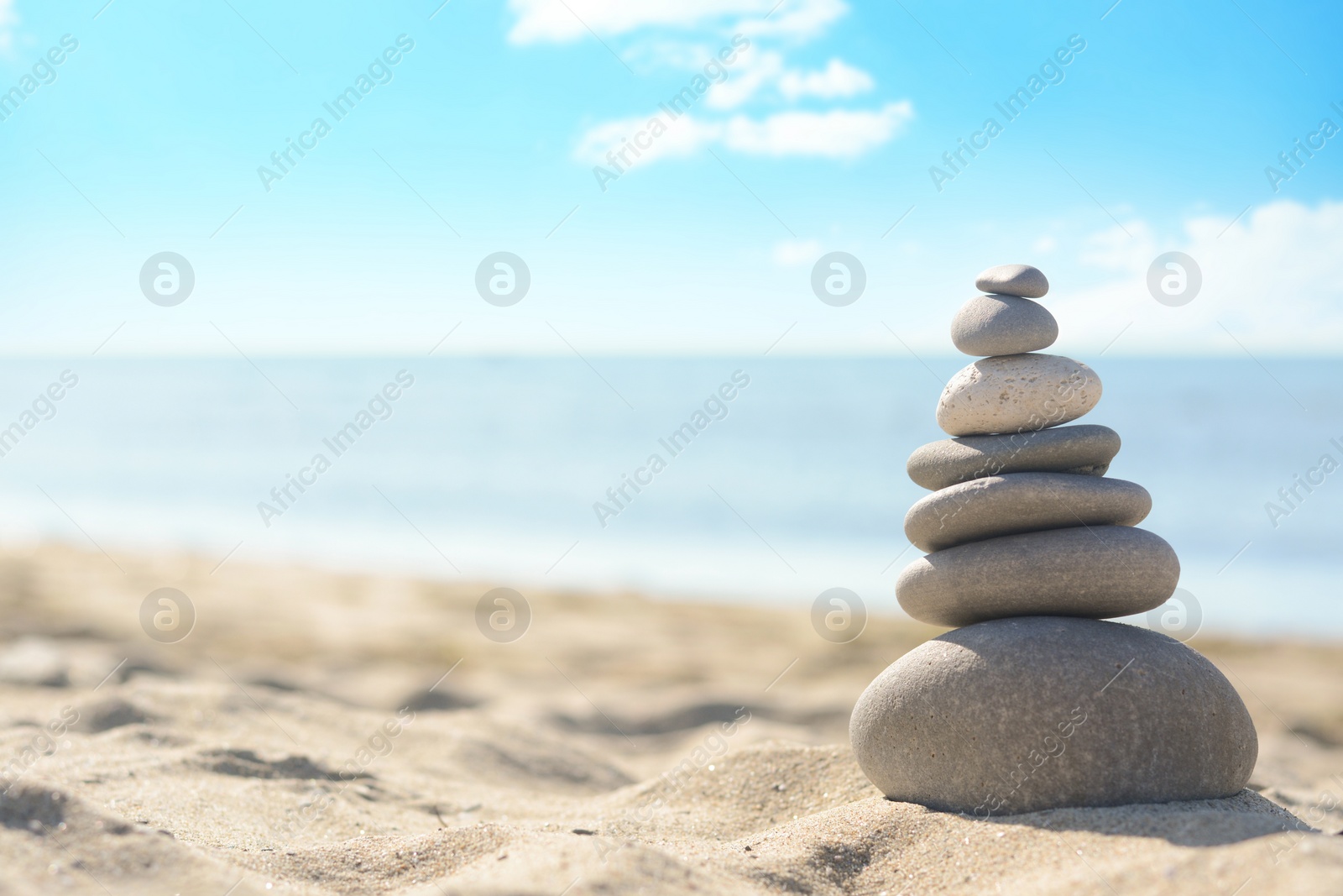 Photo of Stack of stones on sandy beach, space for text