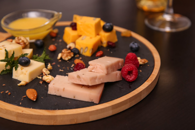 Photo of Different types of delicious cheeses, berries and nuts on table, closeup