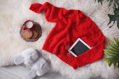 Photo of Flat lay composition with warm sweater and tablet computer on fuzzy carpet