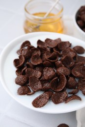 Photo of Breakfast cereal. Chocolate corn flakes and milk in bowl on white tiled table, closeup