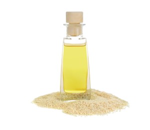 Photo of Glass bottle with fresh sesame oil and seeds isolated on white