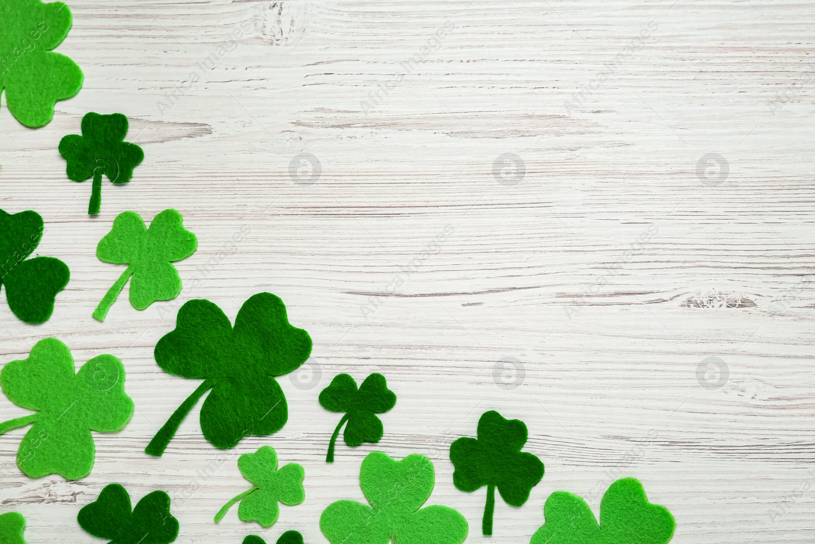 Photo of Decorative clover leaves on white wooden table, flat lay with space for text. Saint Patrick's Day celebration