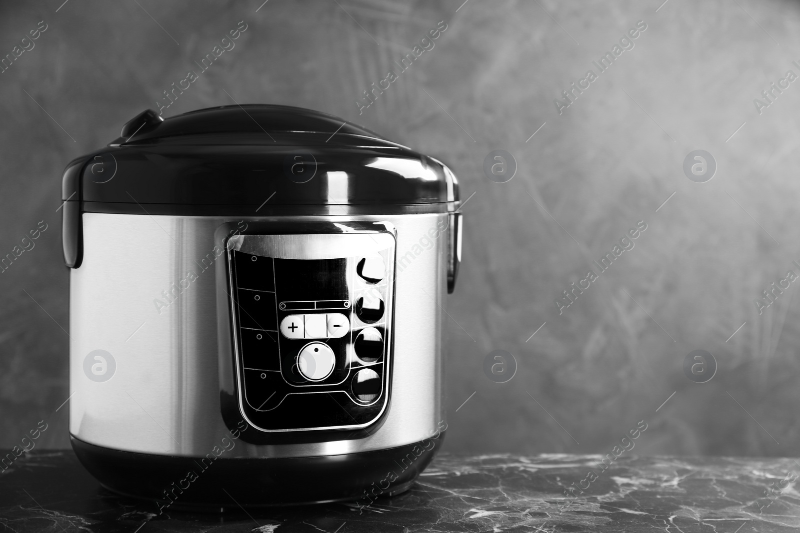 Photo of Modern powerful multi cooker on table against grey background. Space for text