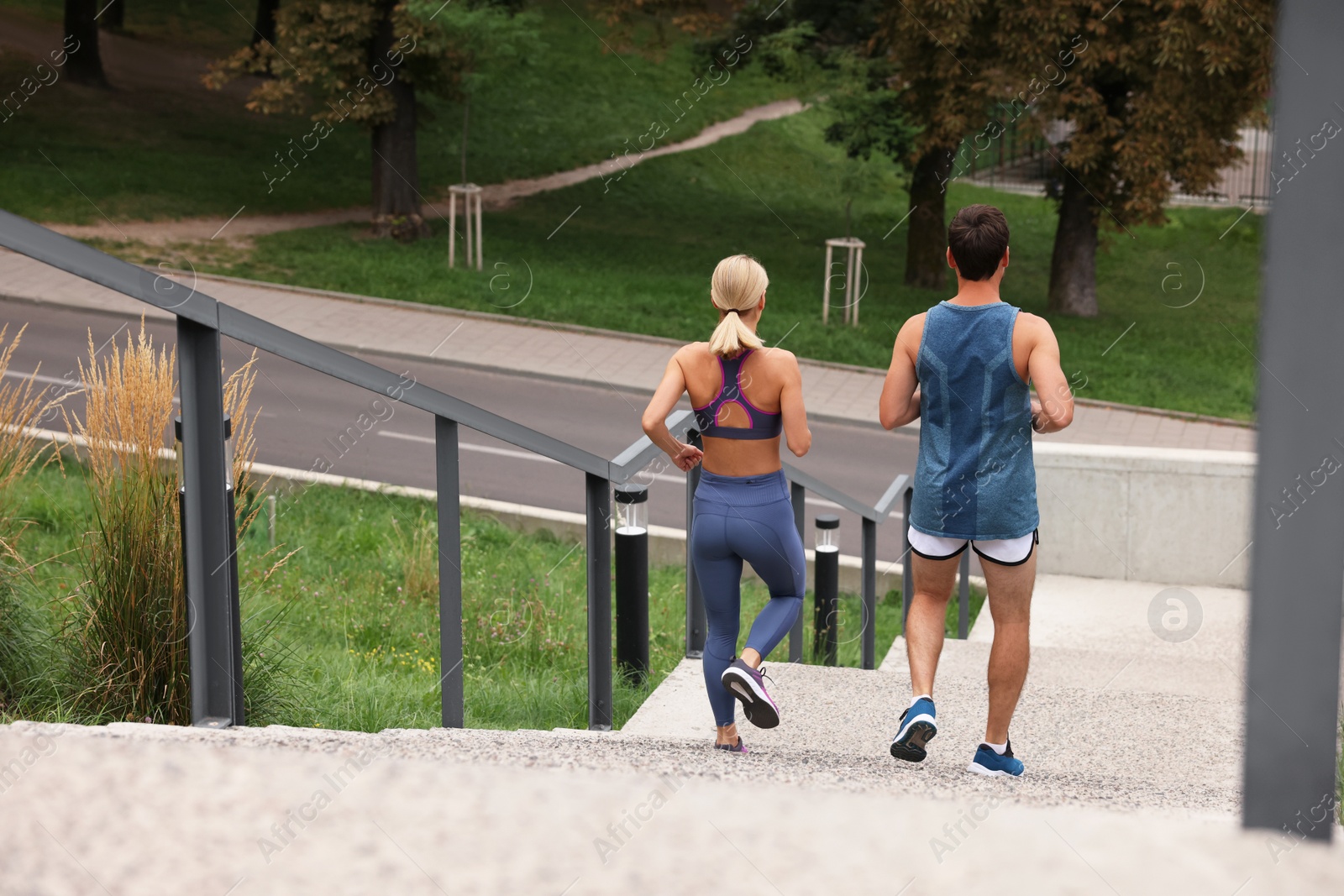 Photo of Healthy lifestyle. Couple running down stairs outdoors, back view