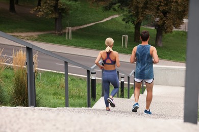 Photo of Healthy lifestyle. Couple running down stairs outdoors, back view