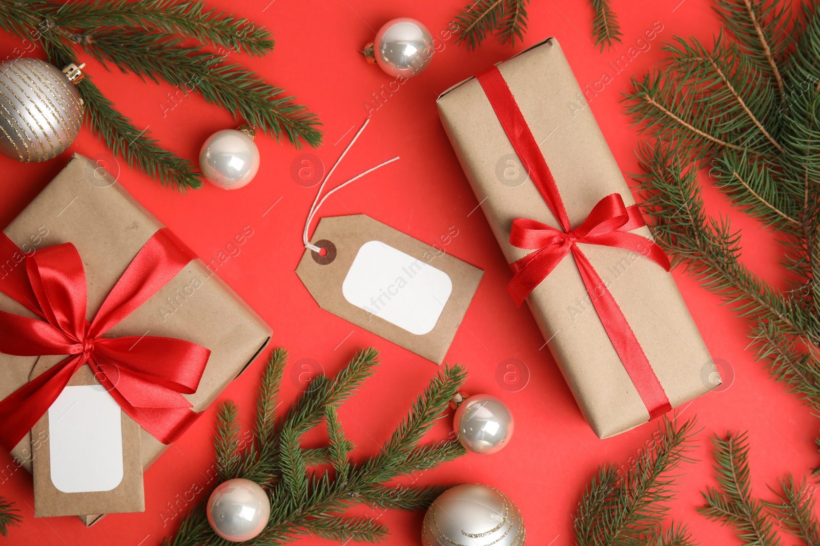 Photo of Flat lay composition with gift boxes and Christmas decor on red background