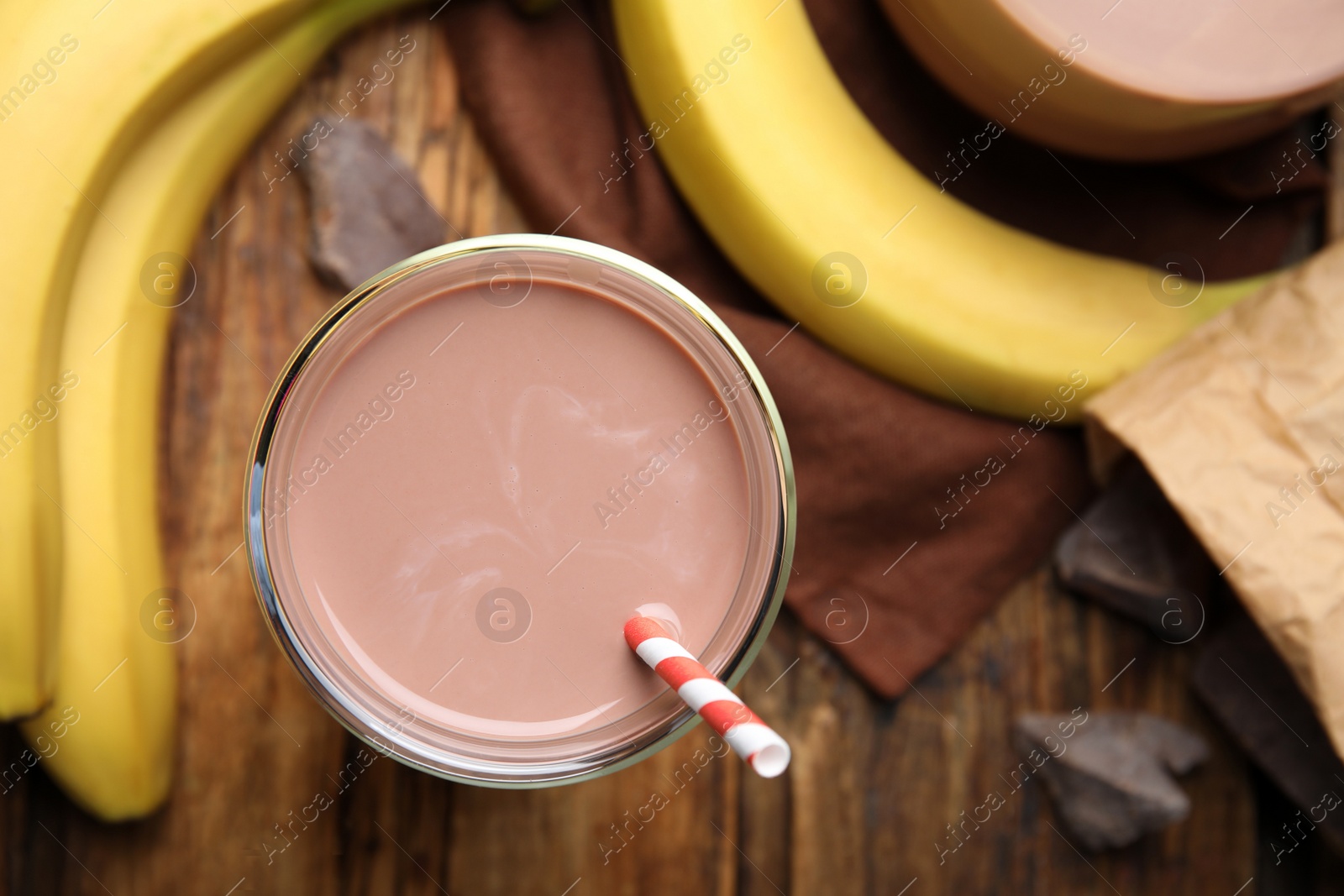 Photo of Fresh yummy chocolate milk on wooden table, flat lay