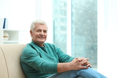 Portrait of handsome mature man on sofa indoors