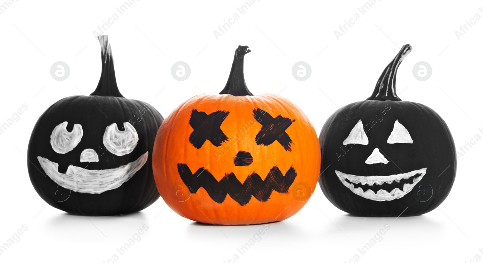 Photo of Halloween pumpkins with scary drawn faces on white background