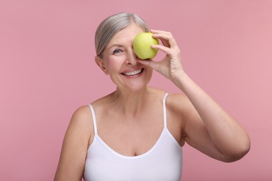 Photo of Beautiful woman with fresh apple on pink background. Vitamin rich food