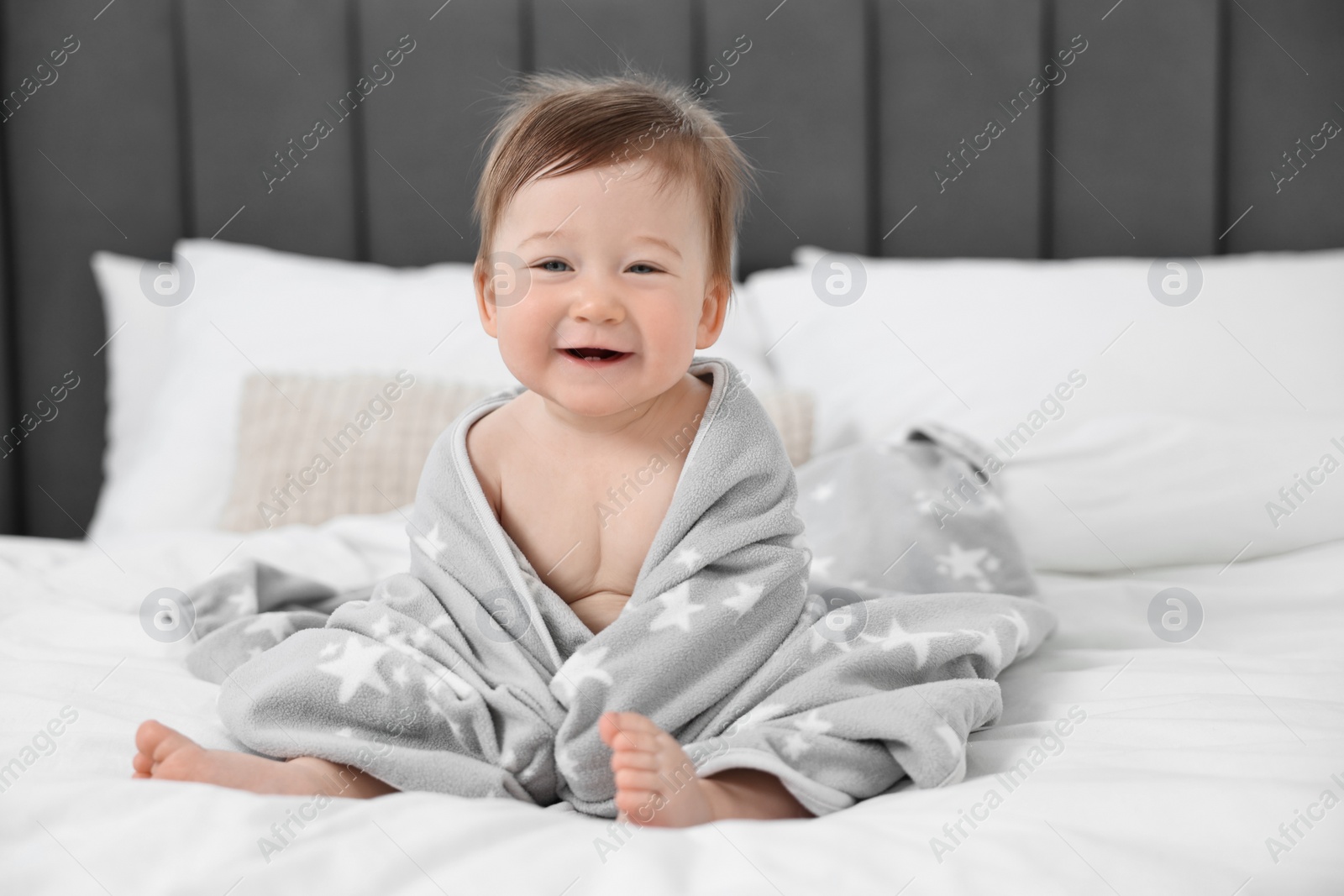 Photo of Happy baby boy with blanket sitting on bed at home