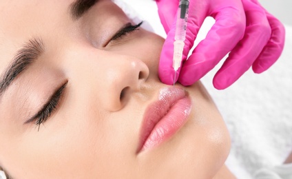 Young woman getting lip injection in beautician salon, closeup