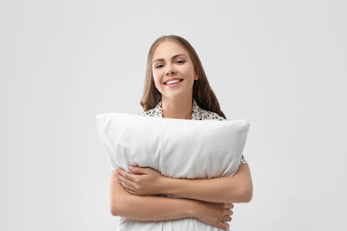 Beautiful woman with pillow on light grey background. Bedtime