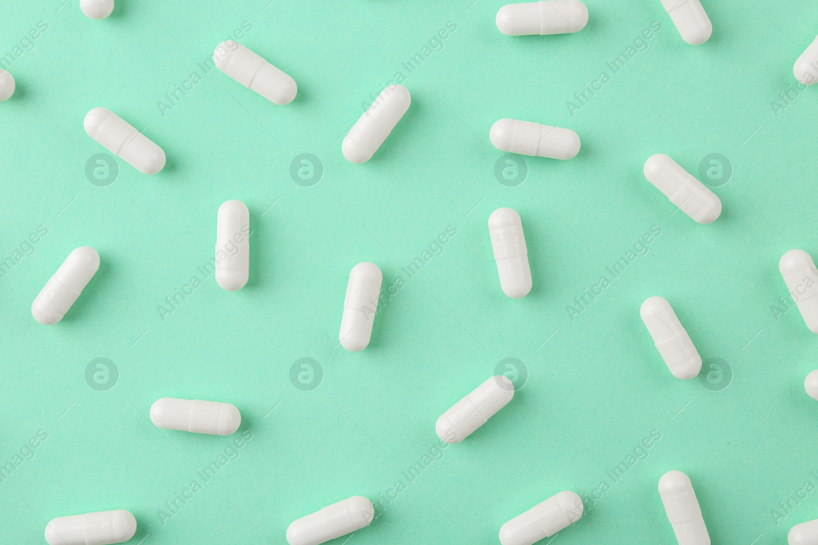 Photo of Vitamin capsules on turquoise background, flat lay