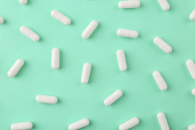 Vitamin capsules on turquoise background, flat lay