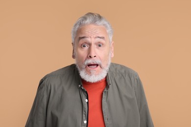 Portrait of surprised senior man on beige background