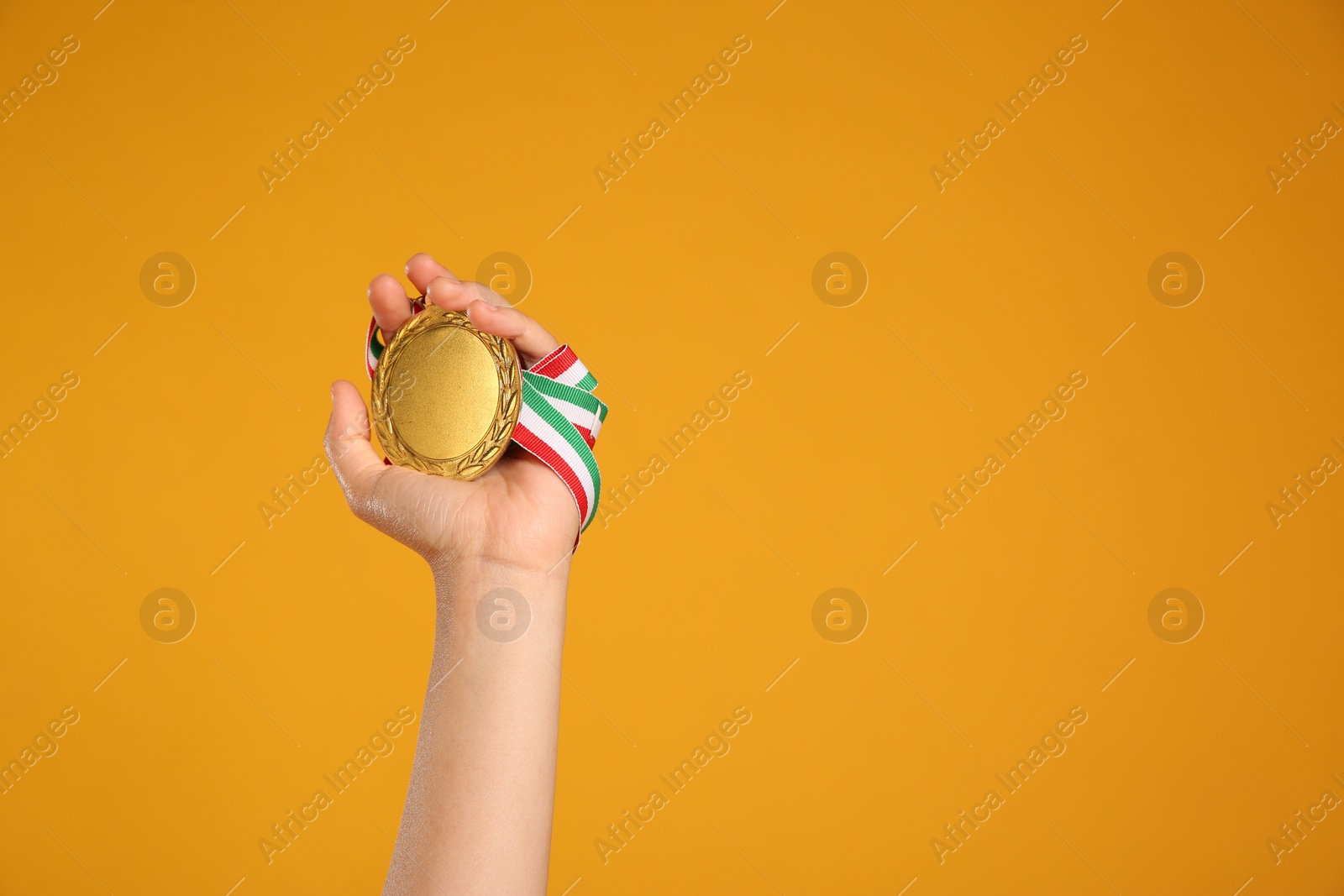 Photo of Woman holding gold medal on yellow background, closeup. Space for text