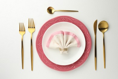 Photo of Stylish setting with cutlery, napkin and plates on white textured table, flat lay