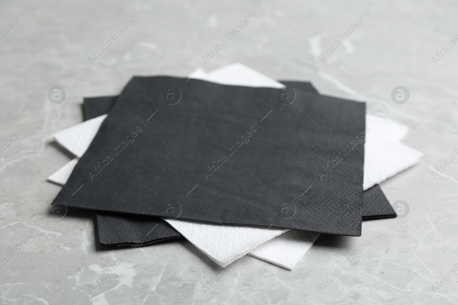 Photo of Clean napkins on grey marble table, closeup. Personal hygiene