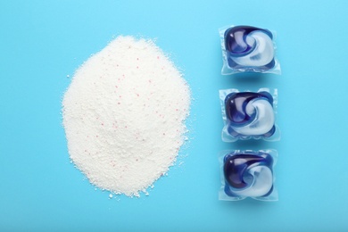 Photo of Laundry capsules and washing powder on turquoise background, flat lay