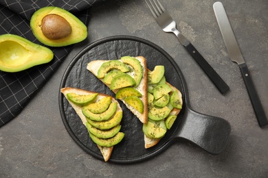 Flat lay composition with avocado toasts on grey table