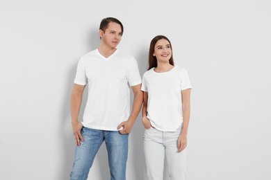 Young couple in stylish jeans on light background