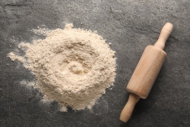 Pile of flour and rolling pin on grey textured table, top view