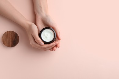 Photo of Woman holding jar of hand cream on pink background, top view. Space for text