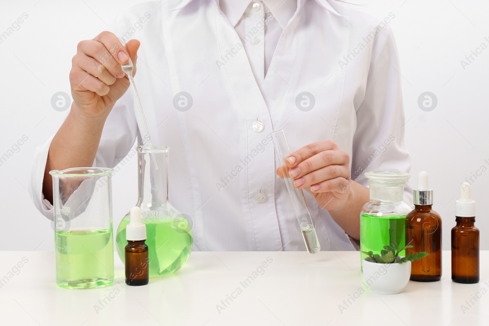 Photo of Female dermatologist creating skin care product at table, closeup