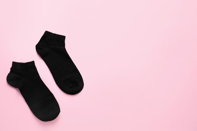 Photo of Pair of black socks on pink background, flat lay. Space for text