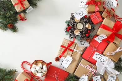 Photo of Christmas advent calendar with gifts and cocoa on white table, flat lay. Space for text