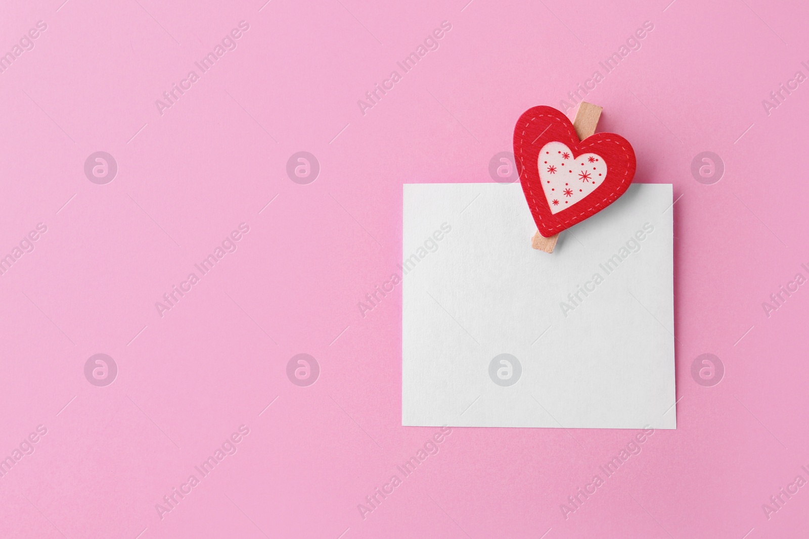 Photo of Blank paper with small heart on pink background, top view. Space for text