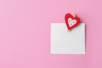 Photo of Blank paper with small heart on pink background, top view. Space for text