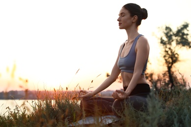 Photo of Young woman practicing yoga outdoors on sunset. Zen meditation