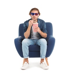 Emotional man with 3D glasses and popcorn sitting in armchair during cinema show on white background