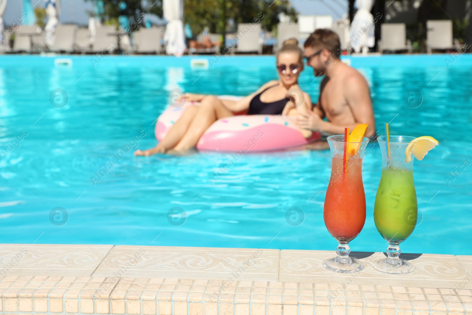 Photo of Refreshing cocktails and young couple in swimming pool on background