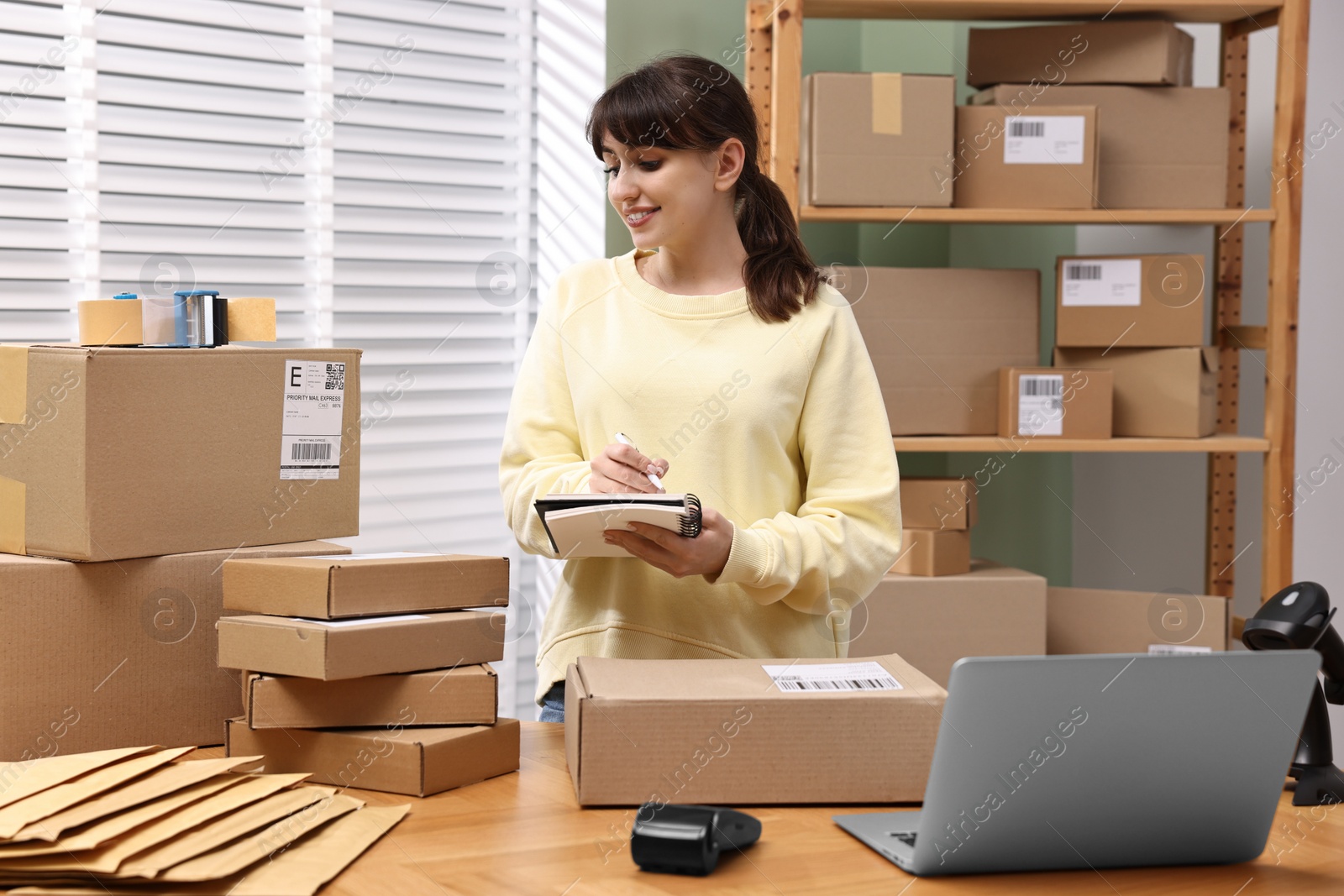 Photo of Parcel packing. Post office worker writing notes indoors